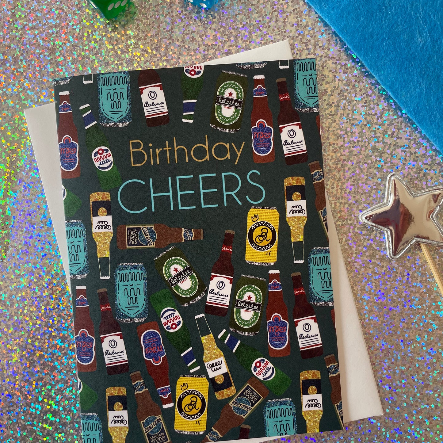 Image shows a birthday card with the greeting 'Birthday Cheers' and a pattern made of collaged beer bottles and cans.