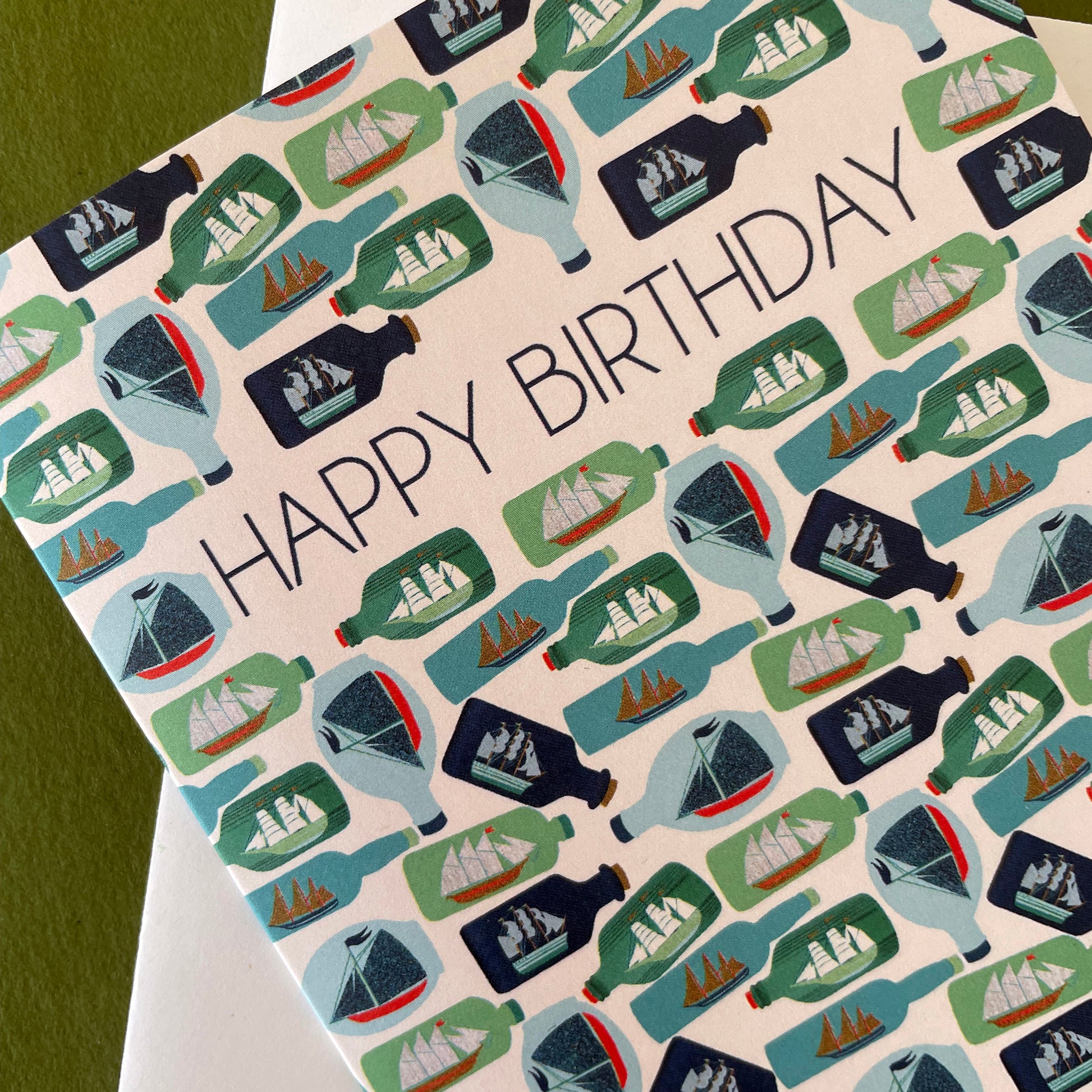 Image shows a birthday card with the greeting 'Happy Birthday' and an illustrated ships in bottles pattern.