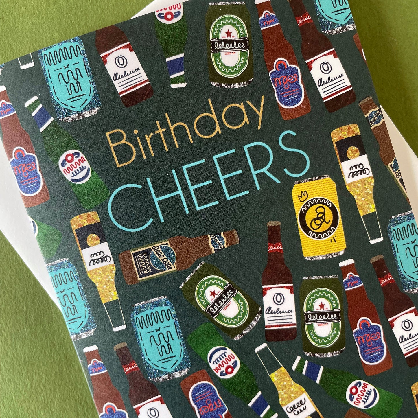 Image shows a birthday card with the greeting 'Birthday Cheers' and a pattern made of collaged beer bottles and cans.