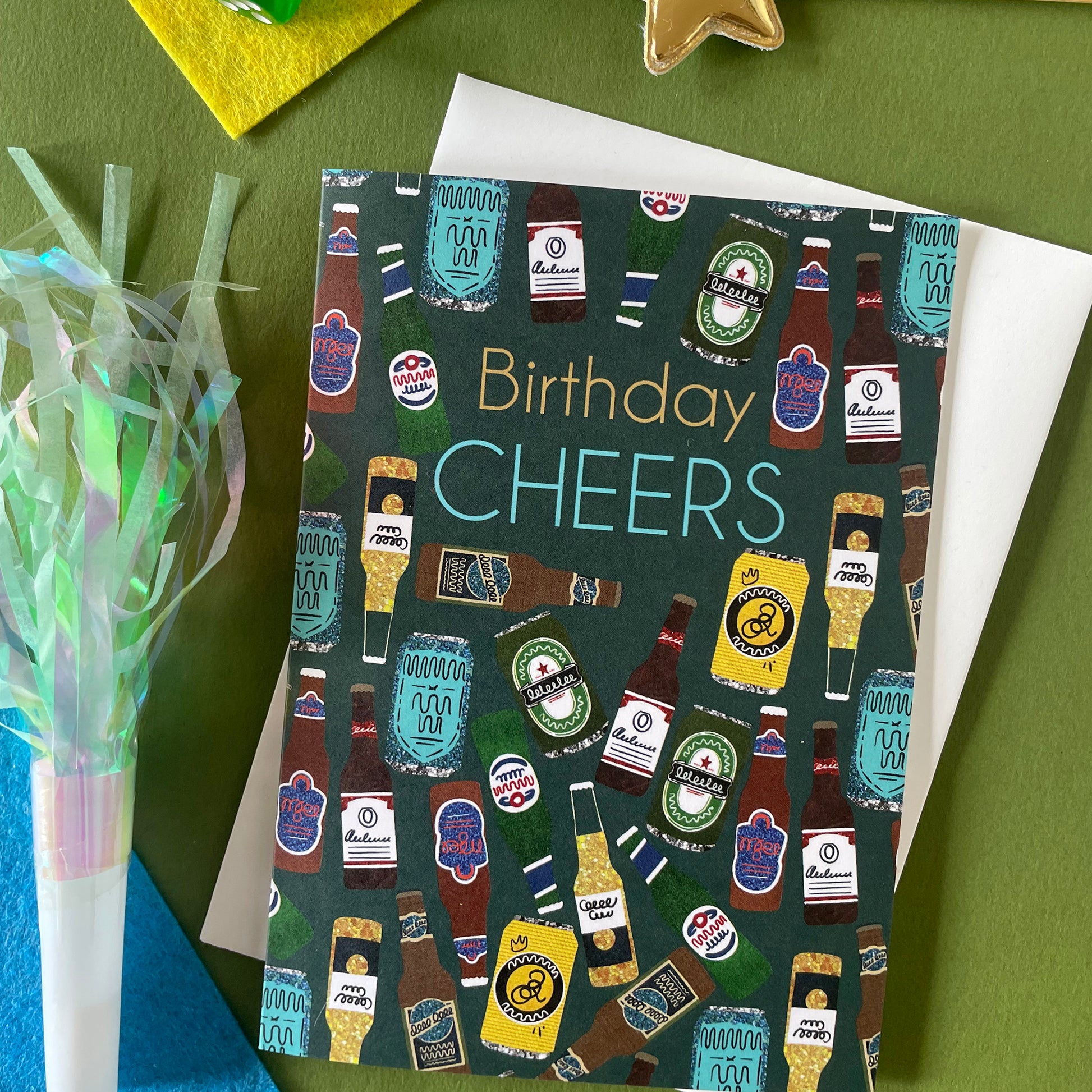 Image shows a birthday card with the greeting 'Birthday Cheers' and a pattern made of collaged beer bottles and cans.