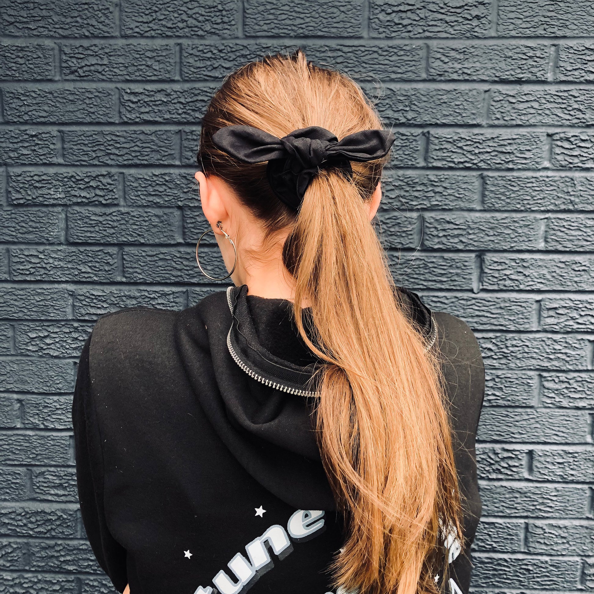 Image shows a black cotton hair scrunchie with a knot and bow