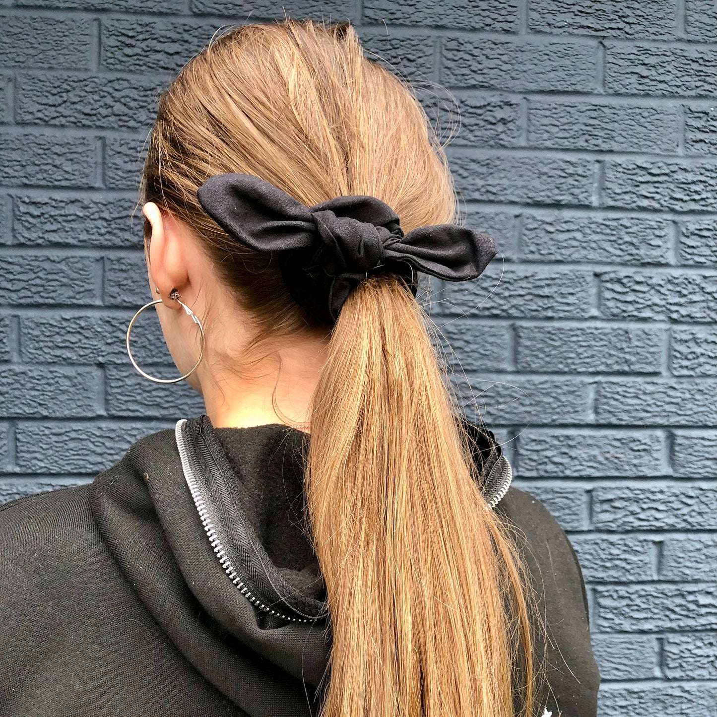 Image shows a black cotton hair scrunchie with a knot and bow