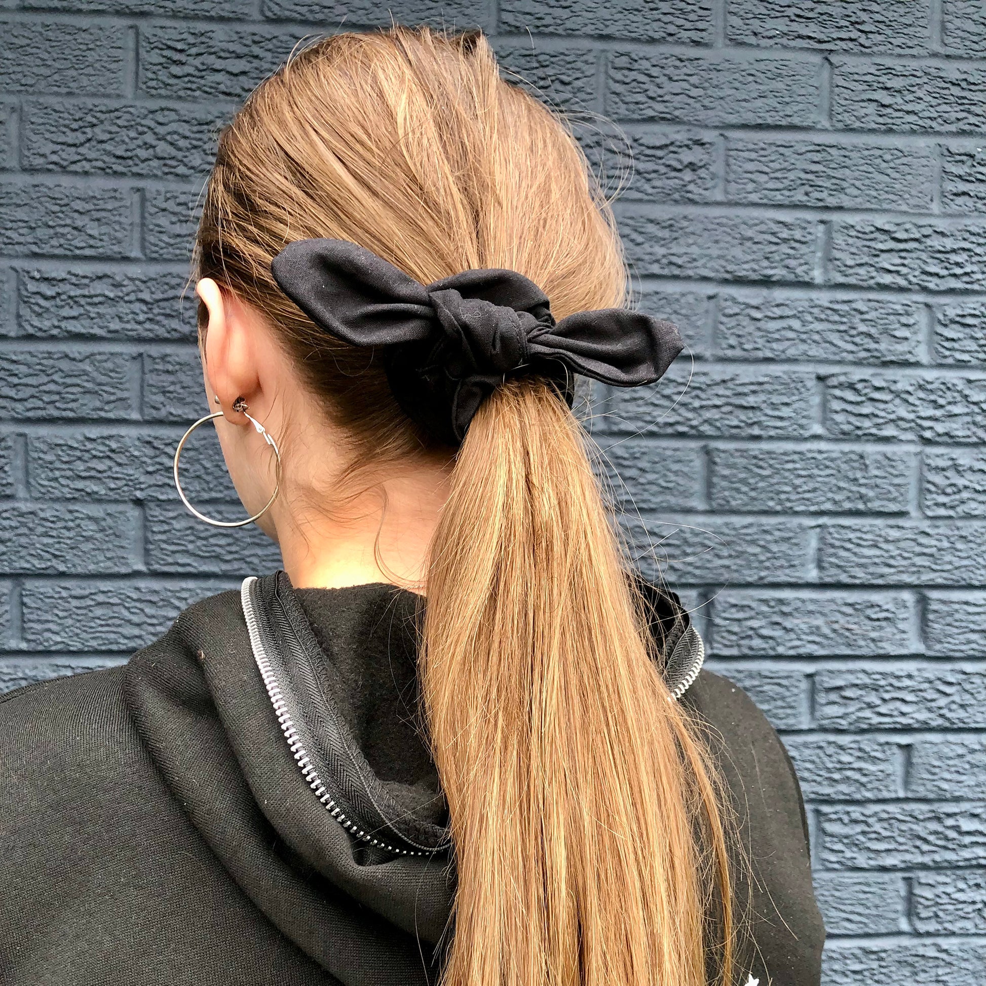 Image shows a black cotton hair scrunchie with a knot and bow