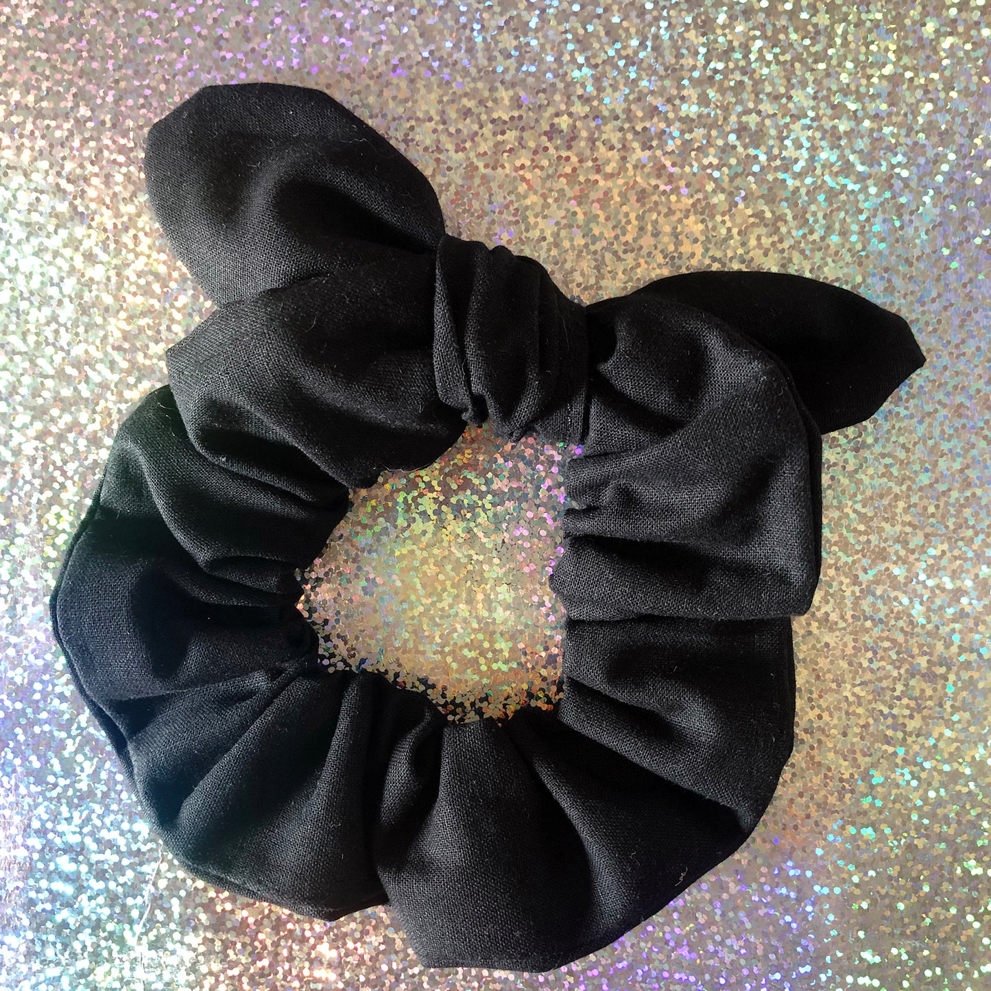 Image shows a black cotton hair scrunchie with a knot and bow