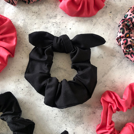 Image shows a black cotton hair scrunchie with a knot and bow