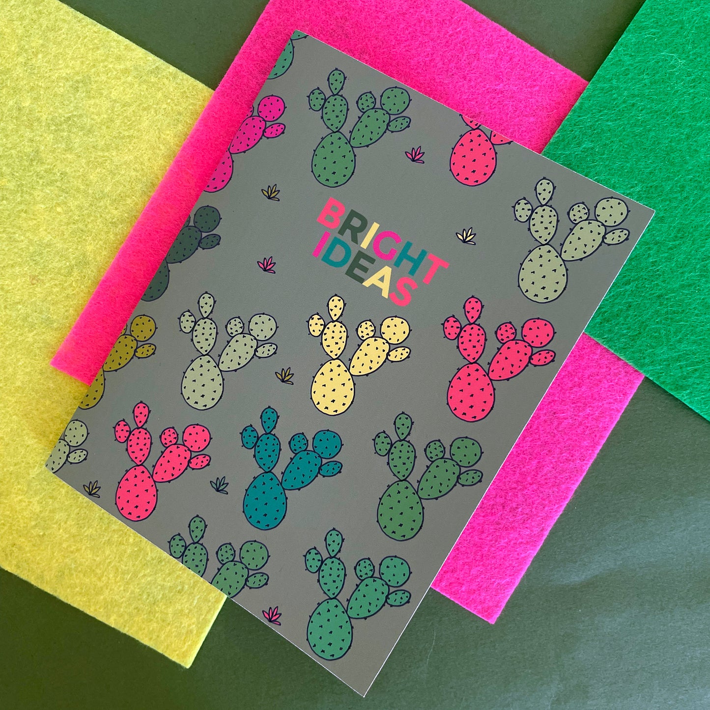 Image shows a pocket size green notebook with a neon cactus print and 'Bright Ideas' written on the front.