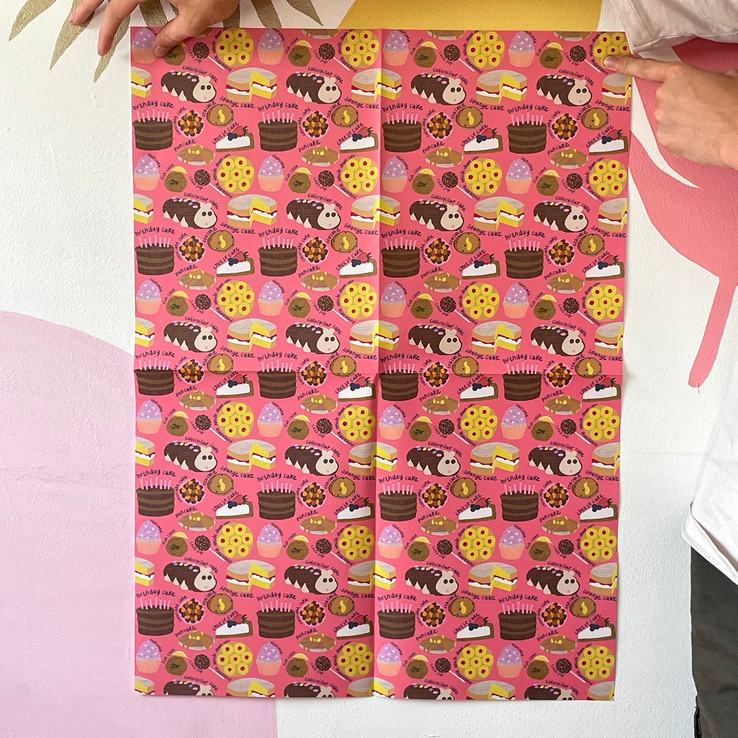 Image shows a pink gift wrap with a fun cake pattern