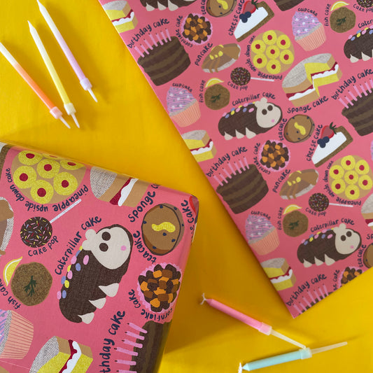Image shows a pink gift wrap with a fun cake pattern