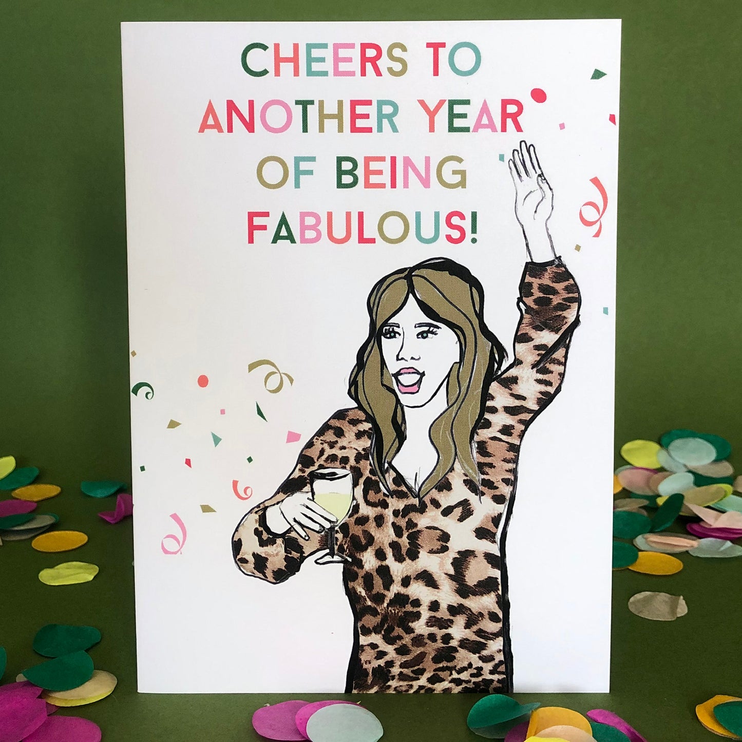 Image shows a fun and fabulous white birthday card with an illustration of a woman in a leopard print top holding a glass of wine and the wording 'Cheers to another year of being fabulous..
