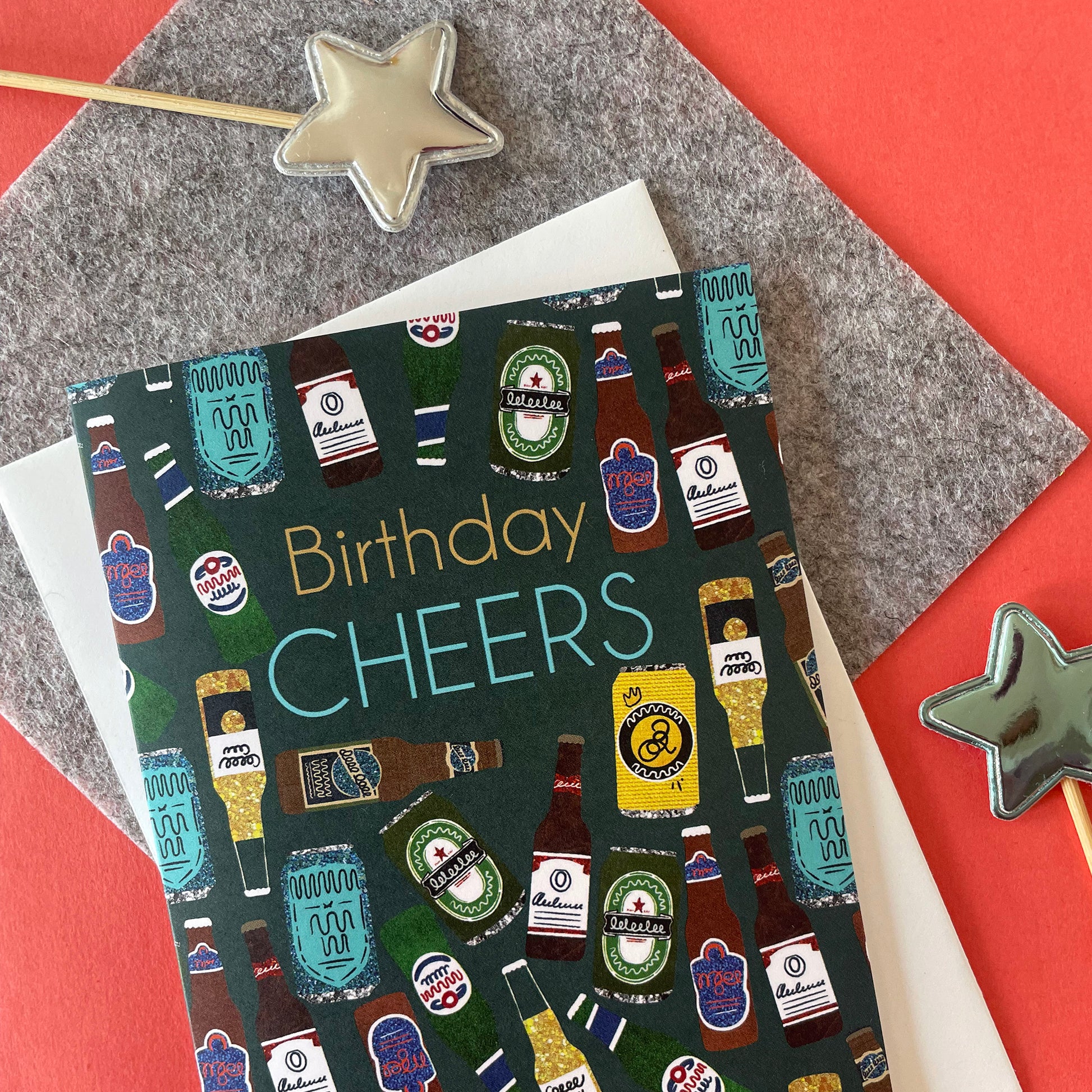 Image shows a birthday card with the greeting 'Birthday Cheers' and a pattern made of collaged beer bottles and cans.