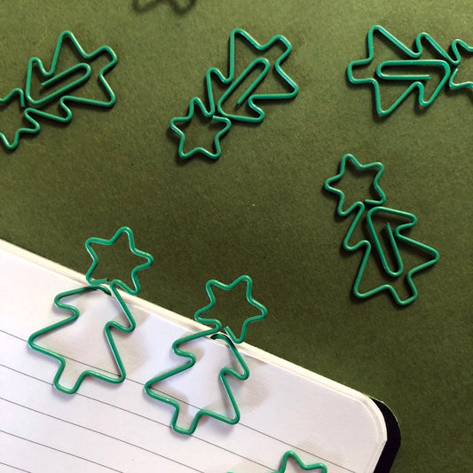 Image shows a collection of cute Christmas tree shaped paperclips on a green background.