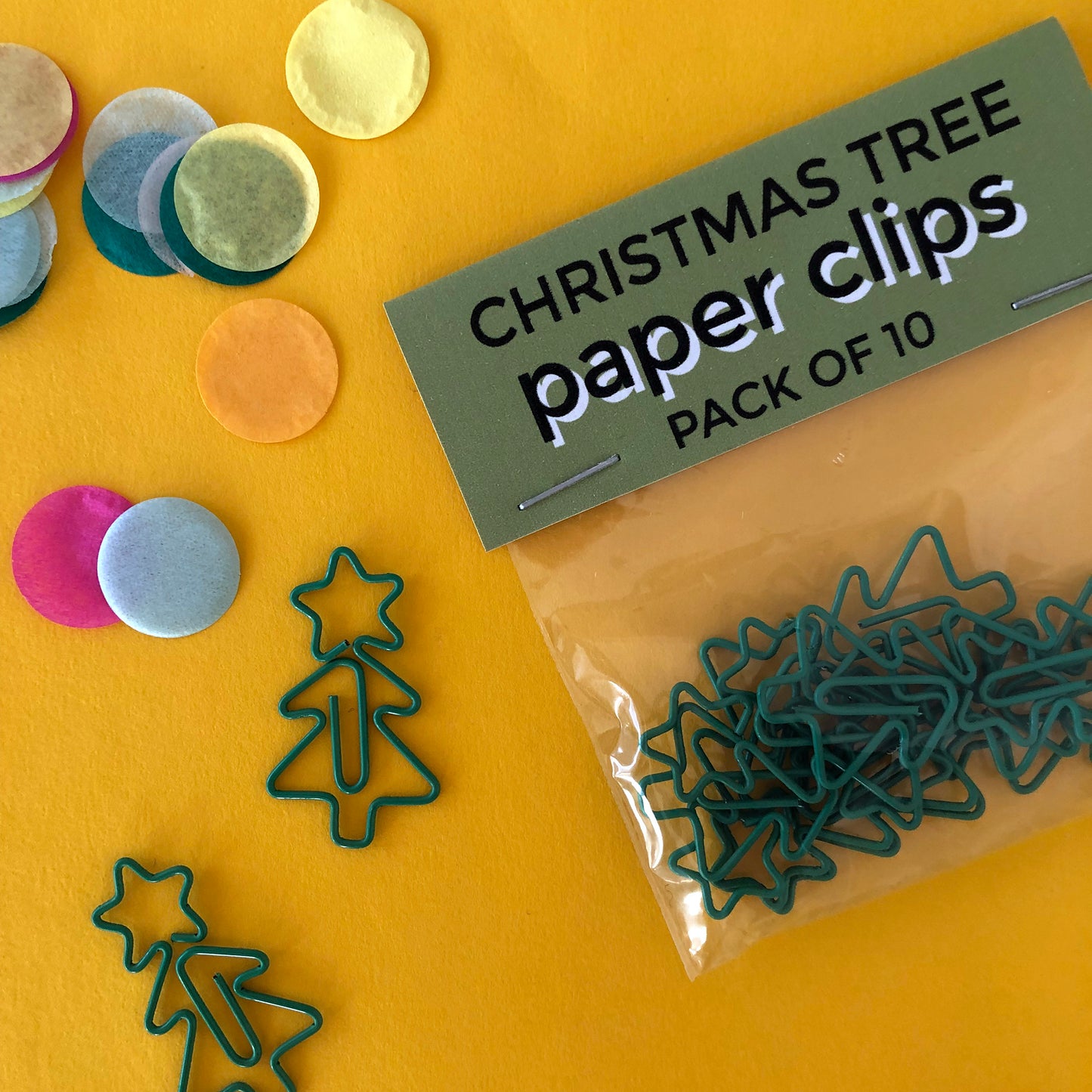 Image shows a collection of cute Christmas tree shaped paperclips on a yellow background.