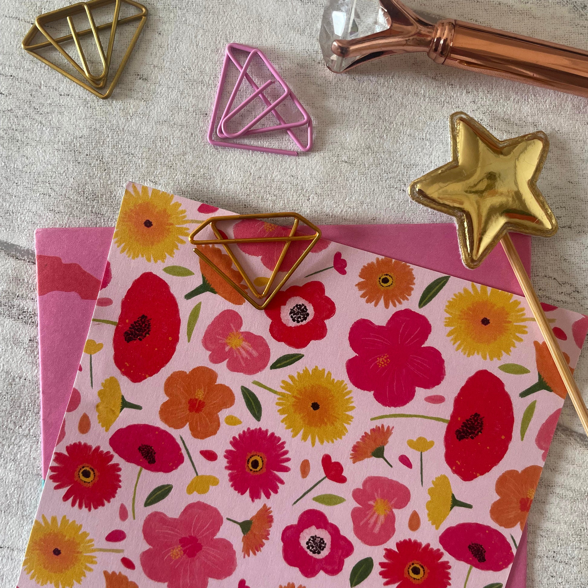 Image shows a set of pink and gold, diamond shaped paperclips.
