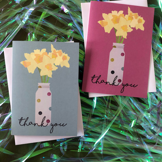 Images shows two greetings cards, one pink and one duck egg blue, both with daffodils in spotty vases and the words 'thank you'