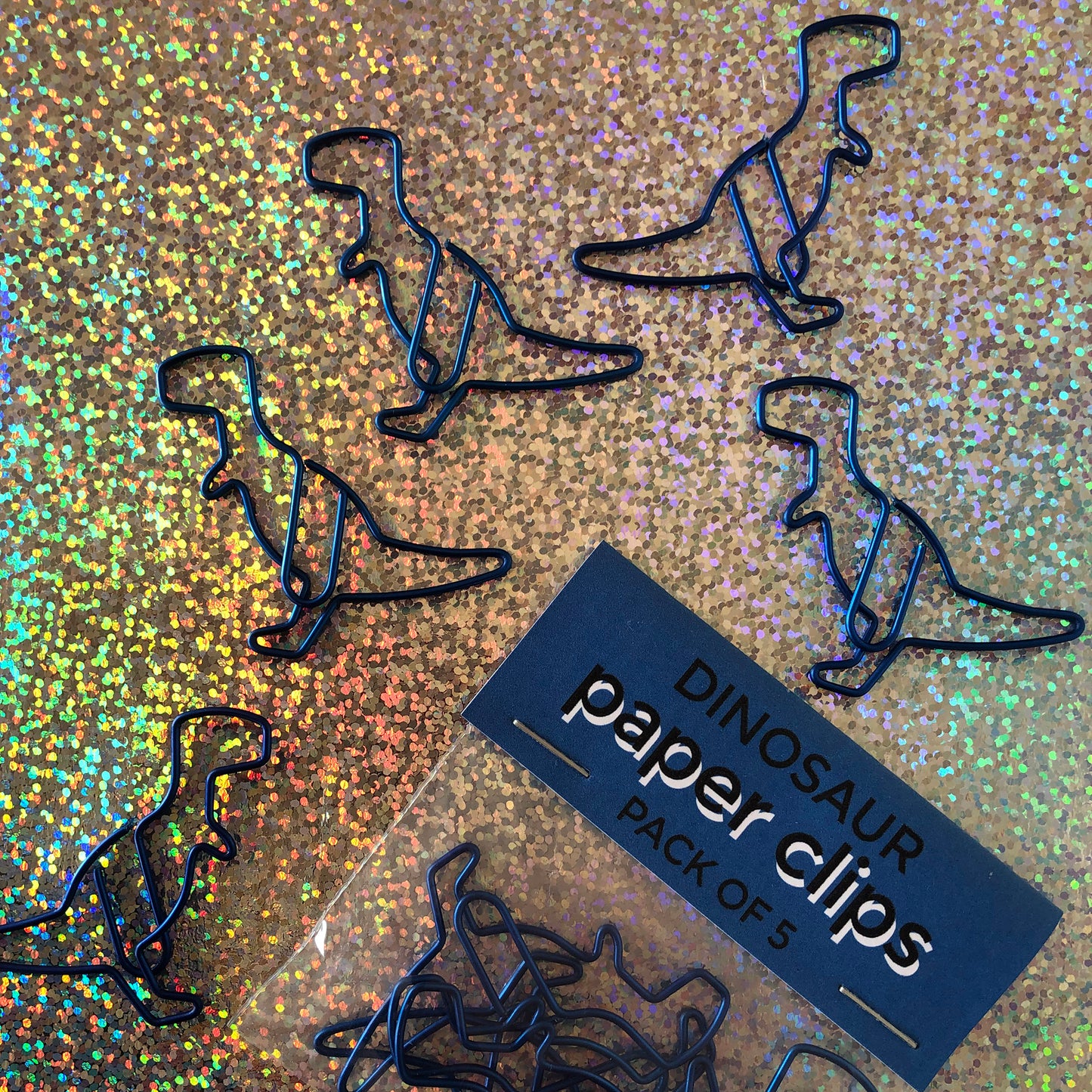Image shows a set of metallic blue dinosaur shaped paperclips.