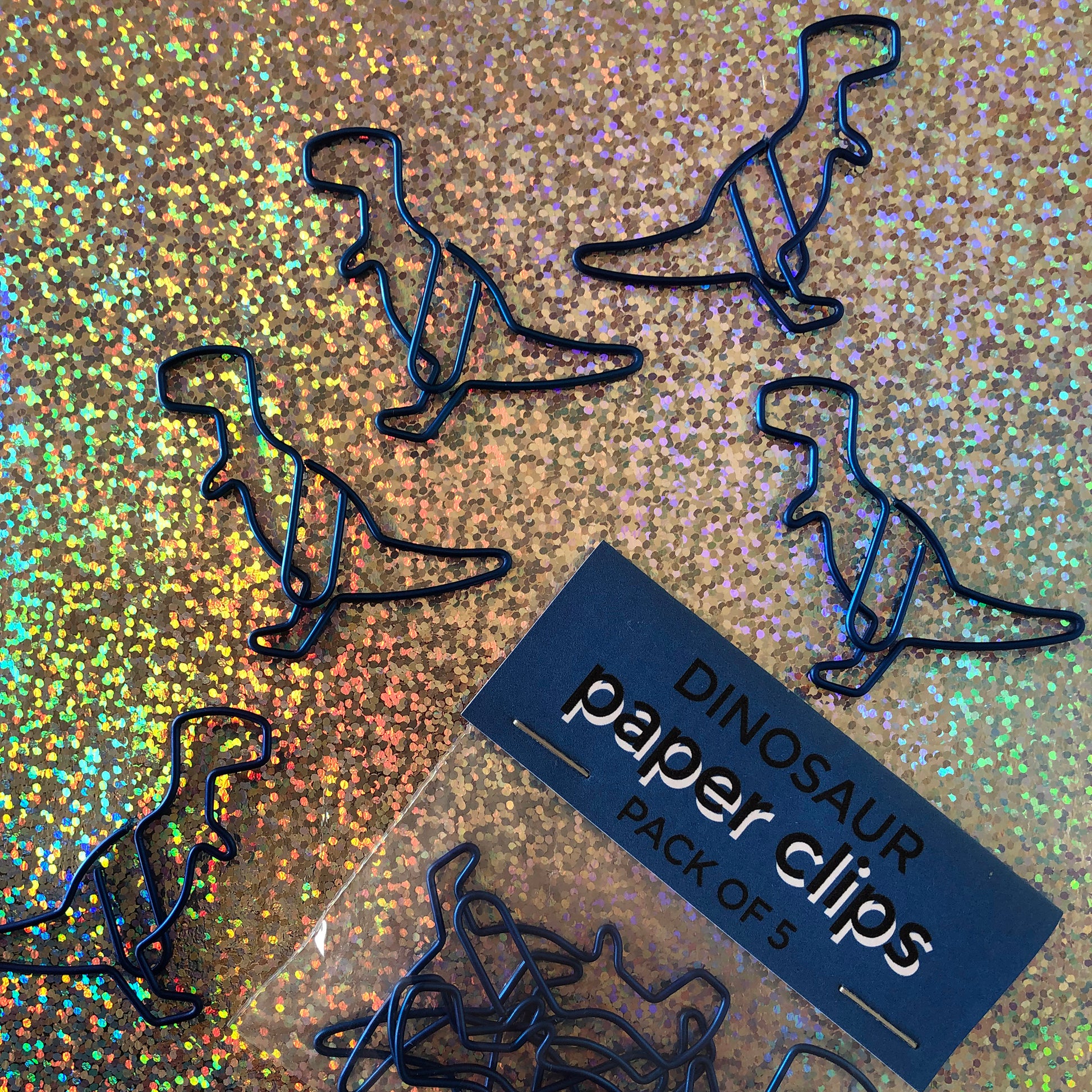 Image shows a set of metallic blue dinosaur shaped paperclips.