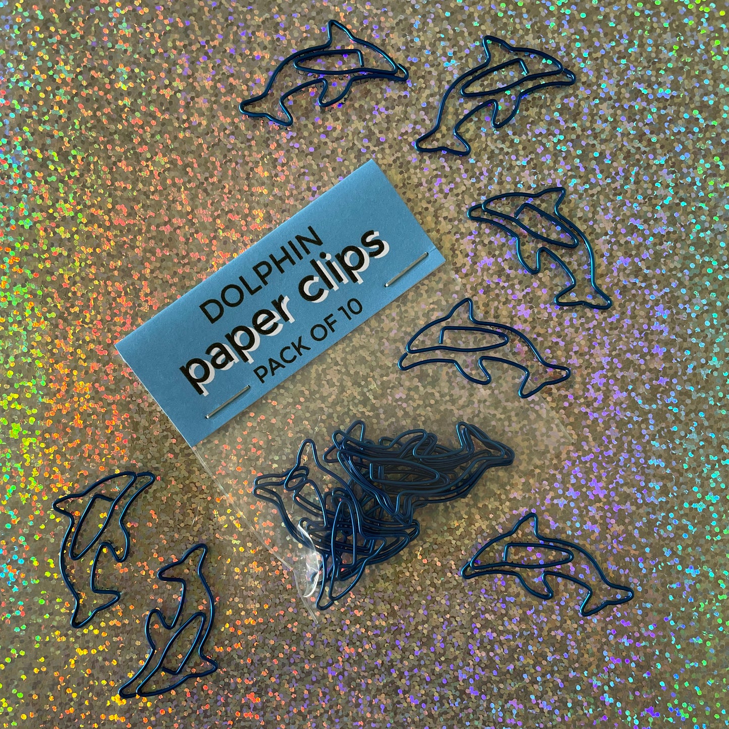 Image shows a fun set of 10 dolphin shaped paper clips in bright, metallic blue