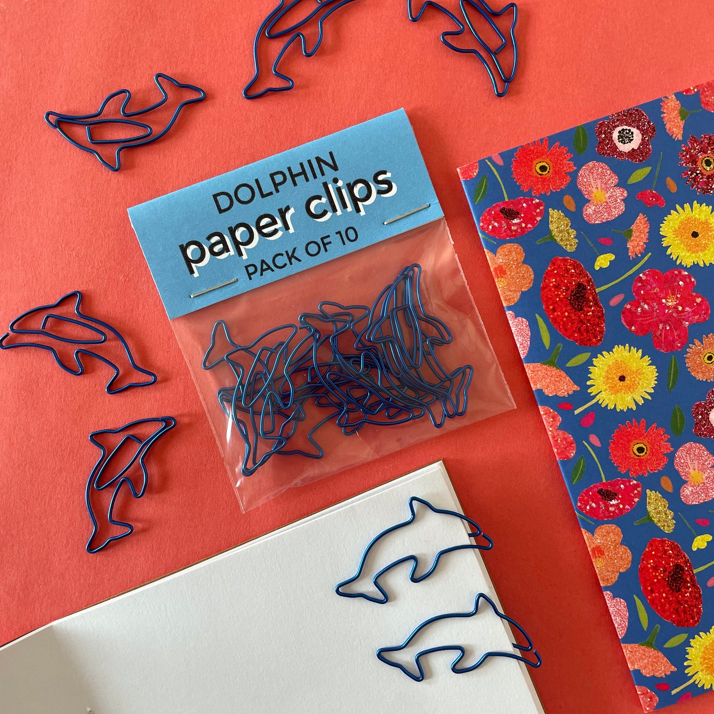 Image shows a fun set of 10 dolphin shaped paper clips in bright, metallic blue