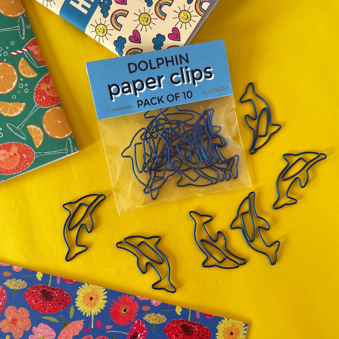 Image shows a fun set of 10 dolphin shaped paper clips in bright, metallic blue