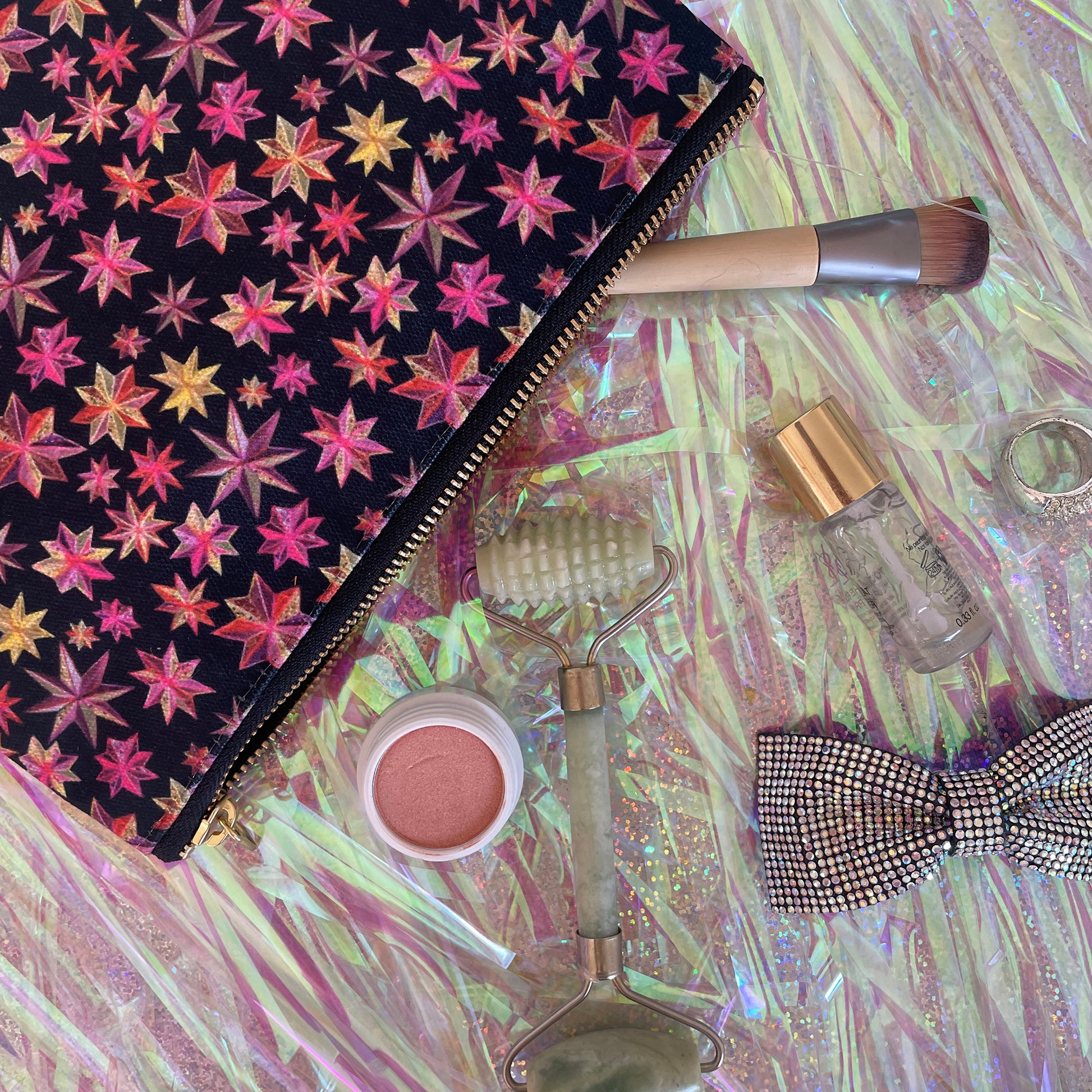 Image shows a black zip pouch with a bright pink, orange and gold starlight lantern design.