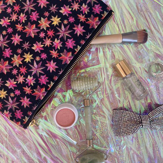 Image shows a black zip pouch with a bright pink, orange and gold starlight lantern design.