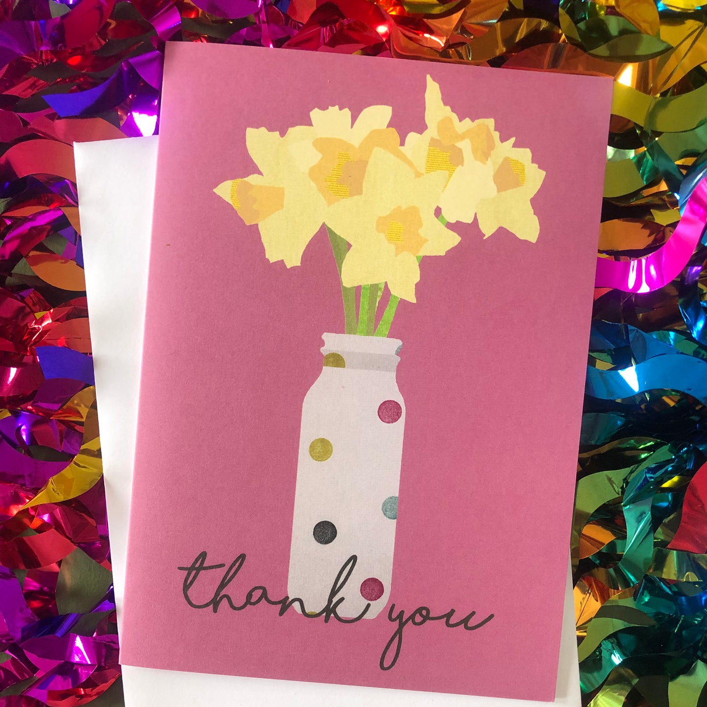 Images shows a pink greetings card with an illustration of daffodils in a spotty vase and the words 'thank you'