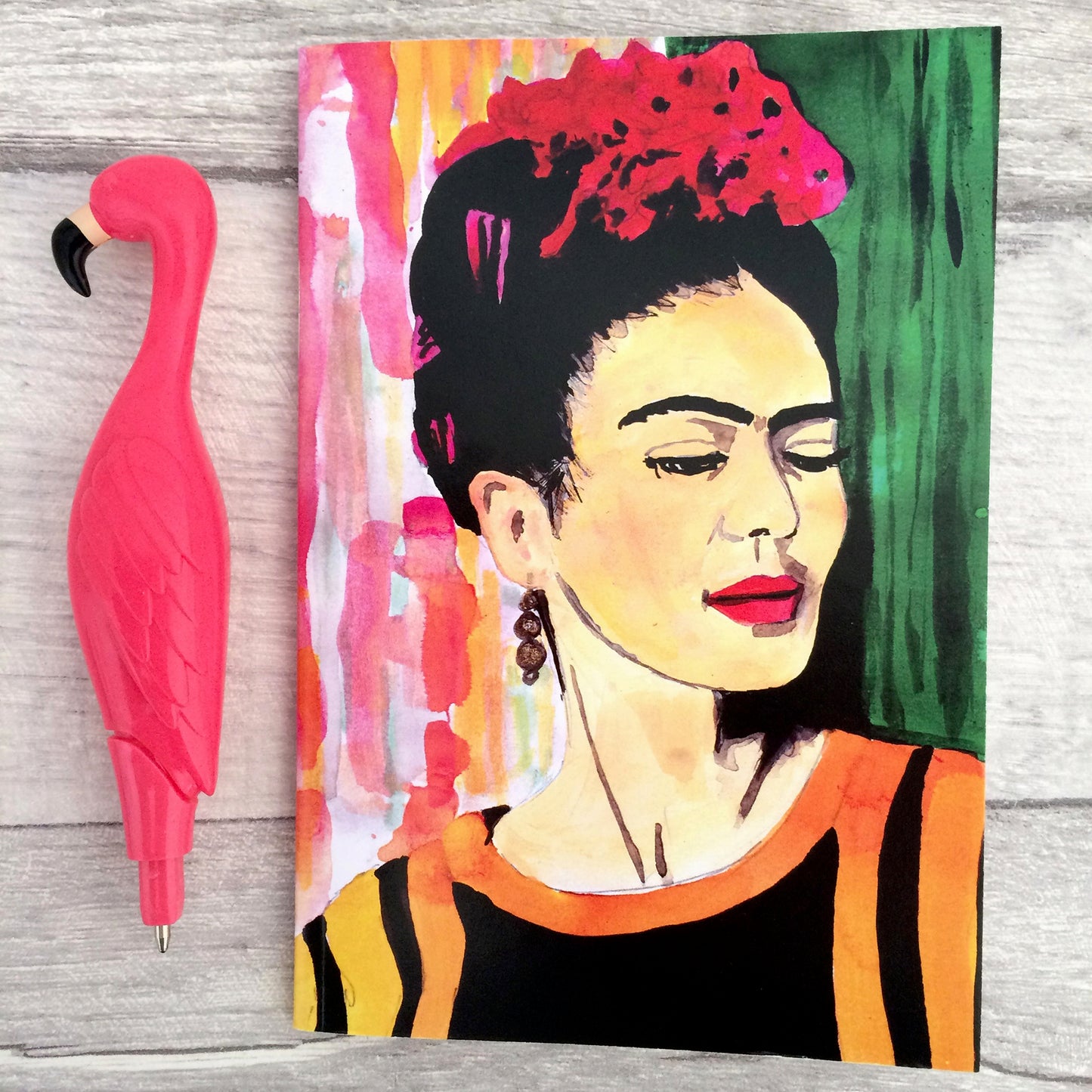 Image shows a full colour notebook featuring a bright, hand painted illustration of Frida Kahlo
