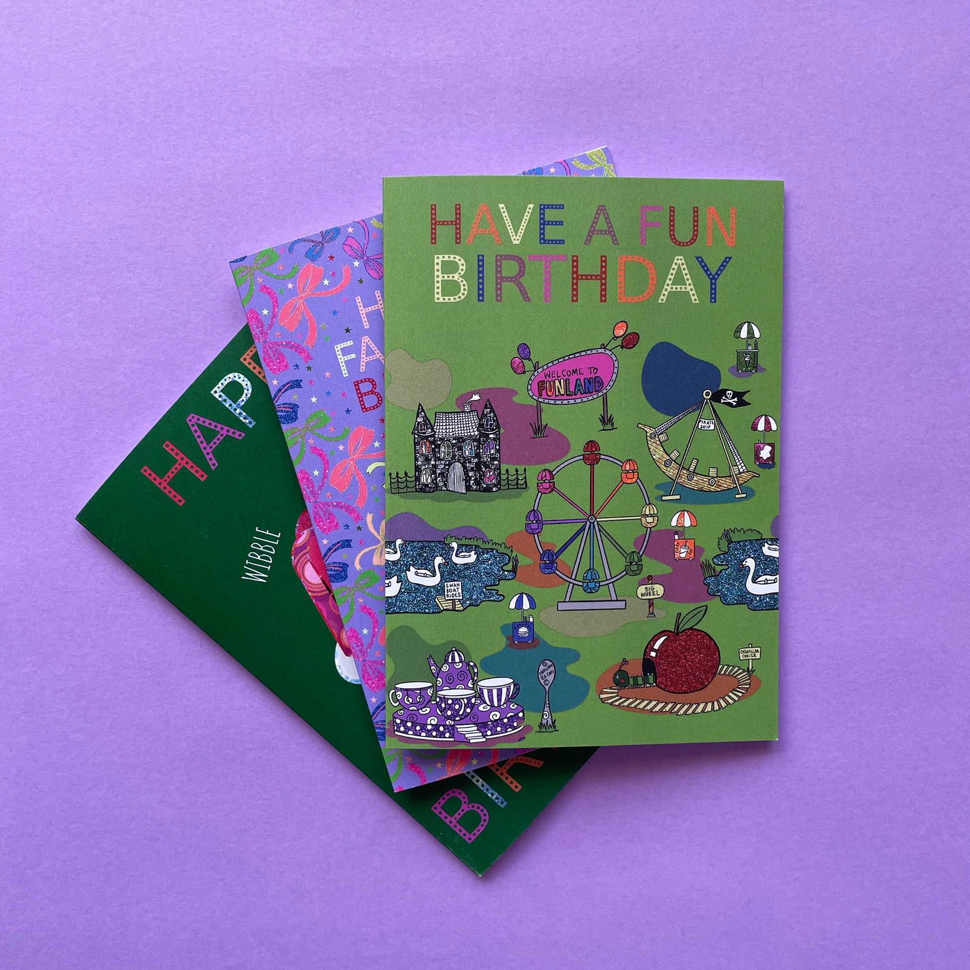 Image shows a green birthday card with illustrations of  vintage theme park rides and the words Have a Fun Birthday