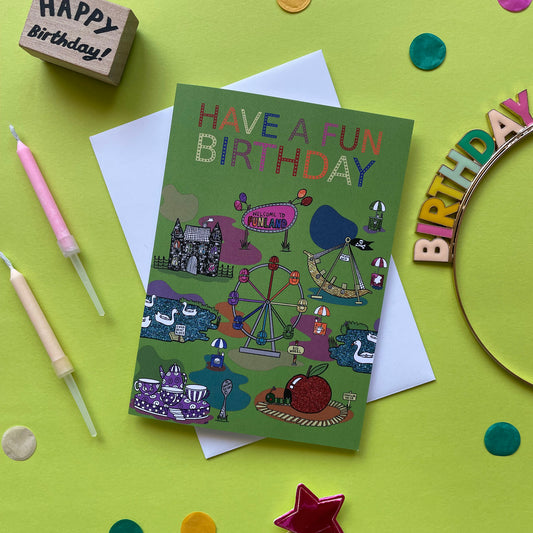Image shows a green birthday card with illustrations of  vintage theme park rides and the words Have a Fun Birthday
