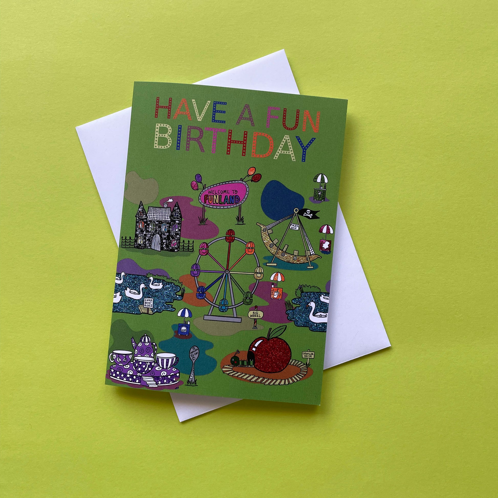 Image shows a green birthday card with illustrations of  vintage theme park rides and the words Have a Fun Birthday