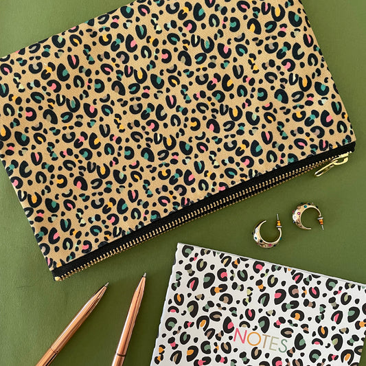 Image shows a beautiful leopard print zip pouch in gold on a green background with accessories.
