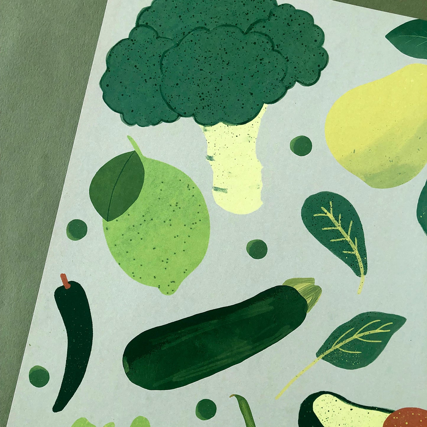 Image of a framed art print of green fruit and vegetables on a green background.