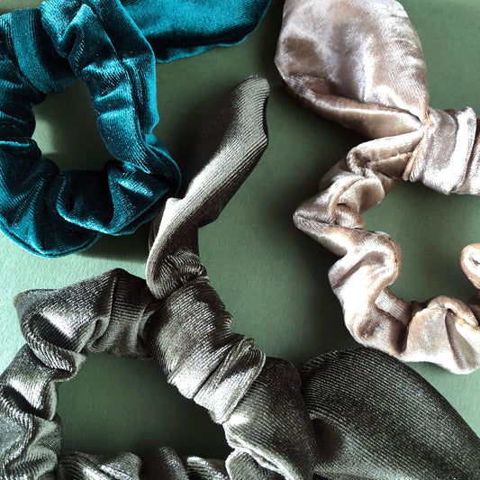Image shows a set of 3 green velvet hair scrunchies each with a knot and bow