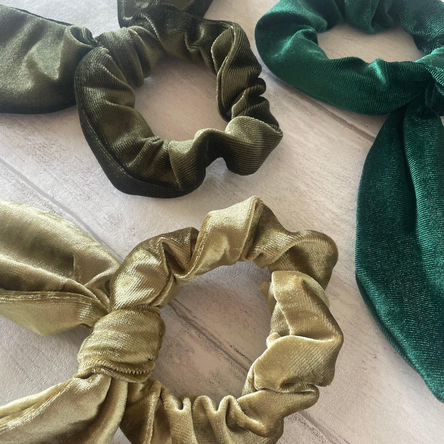 Image shows a set of 3 green velvet hair scrunchies each with a knot and bow