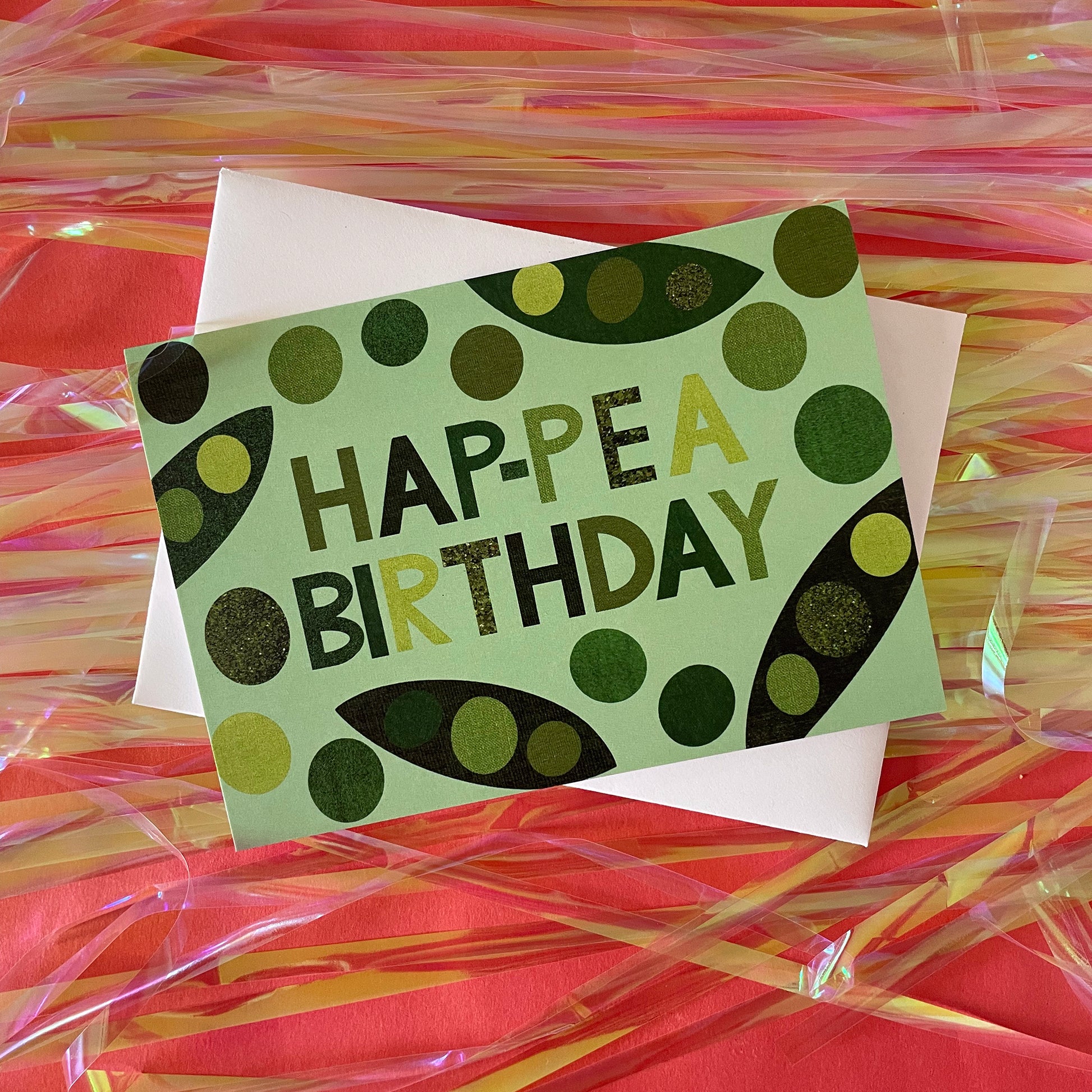 Image of a light green card that says Hap-pea Birthday in bold lettering and has collaged illustrations of peas and pods
