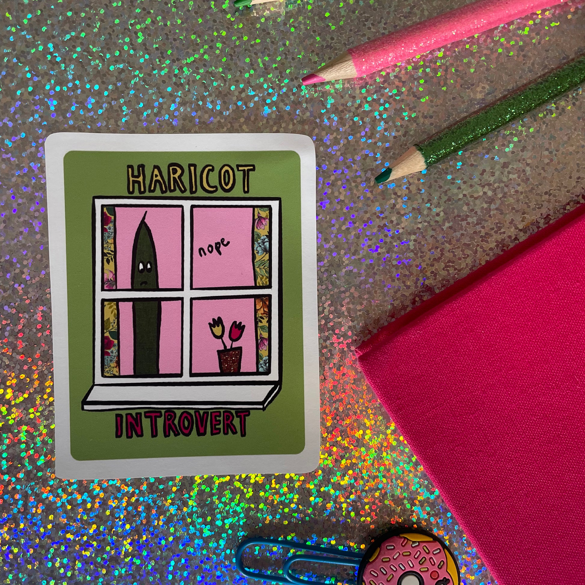 Image shows a green, rectangular sticker with an illustration of a green bean looking out of a window and the words 'Haricot Introvert'