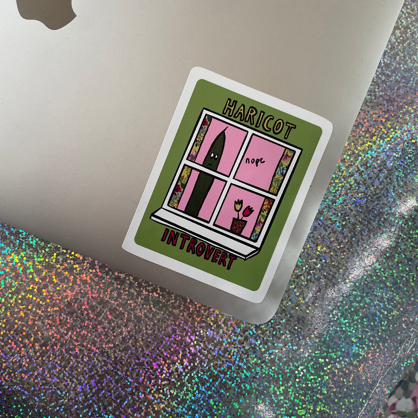 Image shows a green, rectangular sticker with an illustration of a green bean looking out of a window and the words 'Haricot Introvert'
