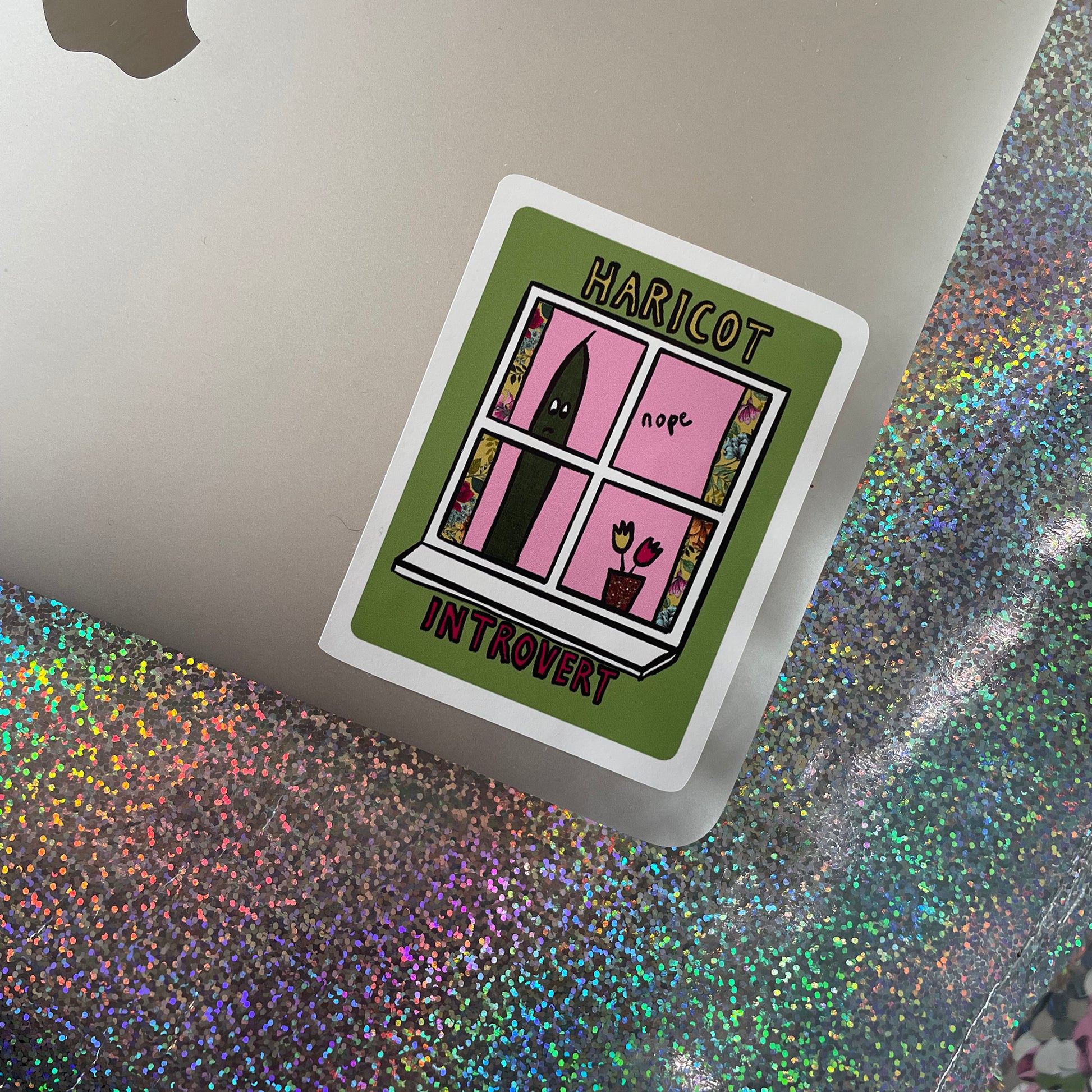 Image shows a green, rectangular sticker with an illustration of a green bean looking out of a window and the words 'Haricot Introvert'