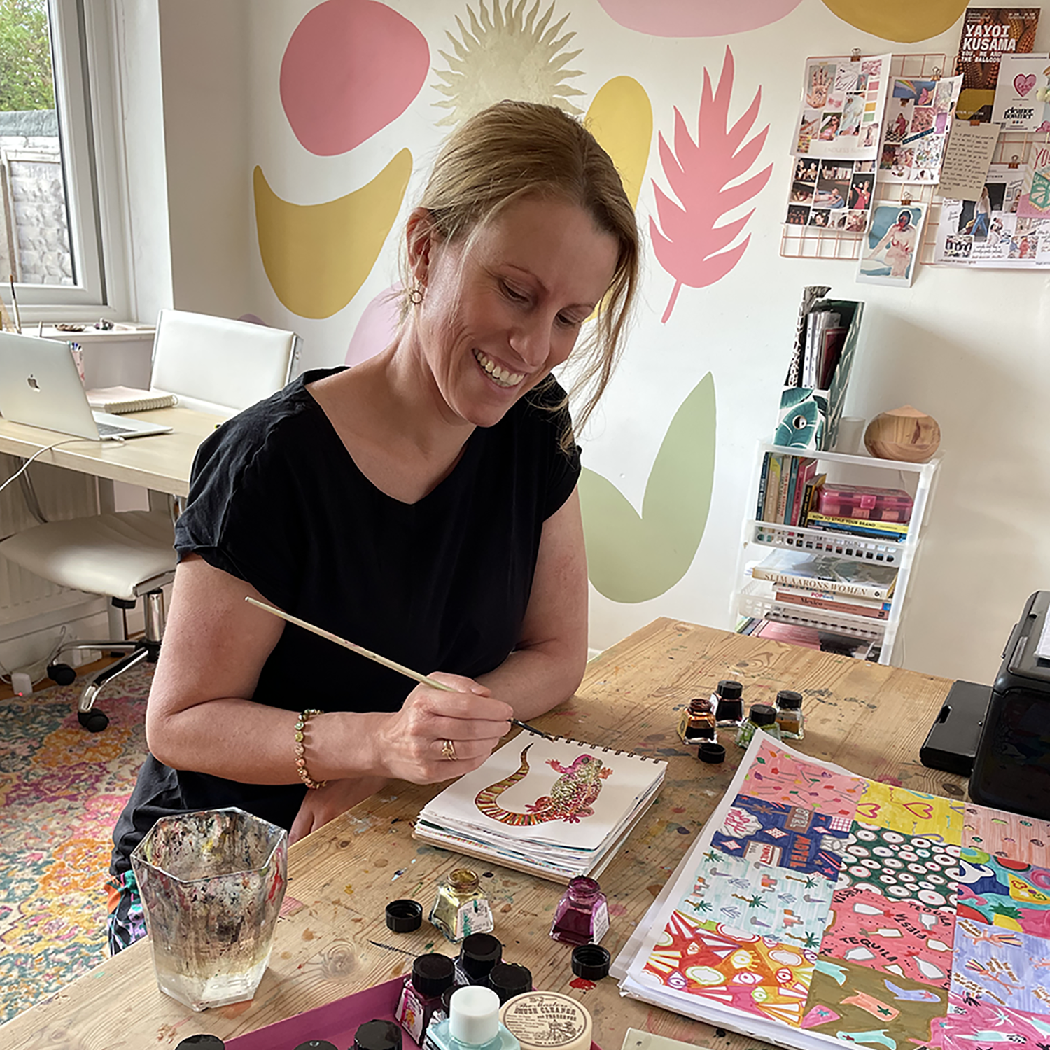Image of Kat Arnold of Katsillustration working at a desk in her studio