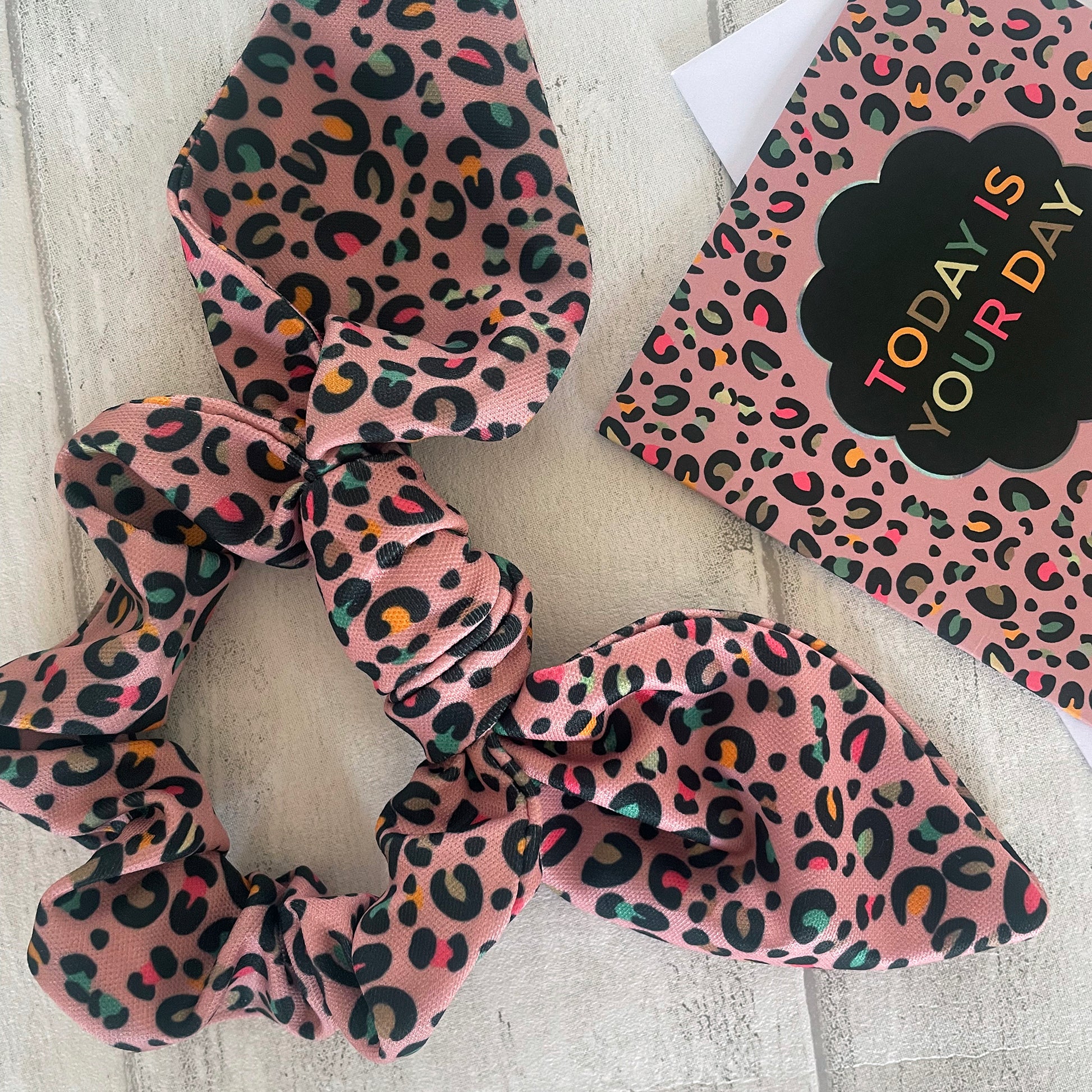 Image shows a pink leopard print hair scrunchie with a knot and bow