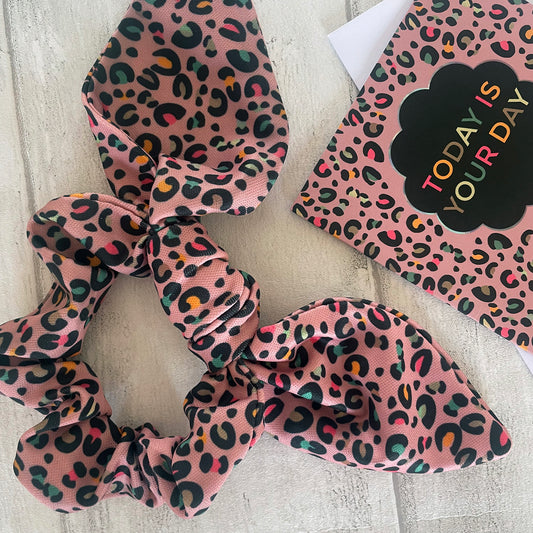 Image shows a pink leopard print hair scrunchie with a knot and bow