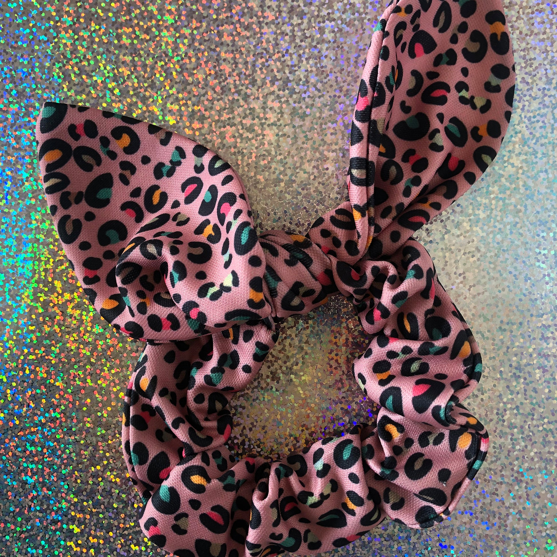 Image shows a pink leopard print hair scrunchie with a knot and bow