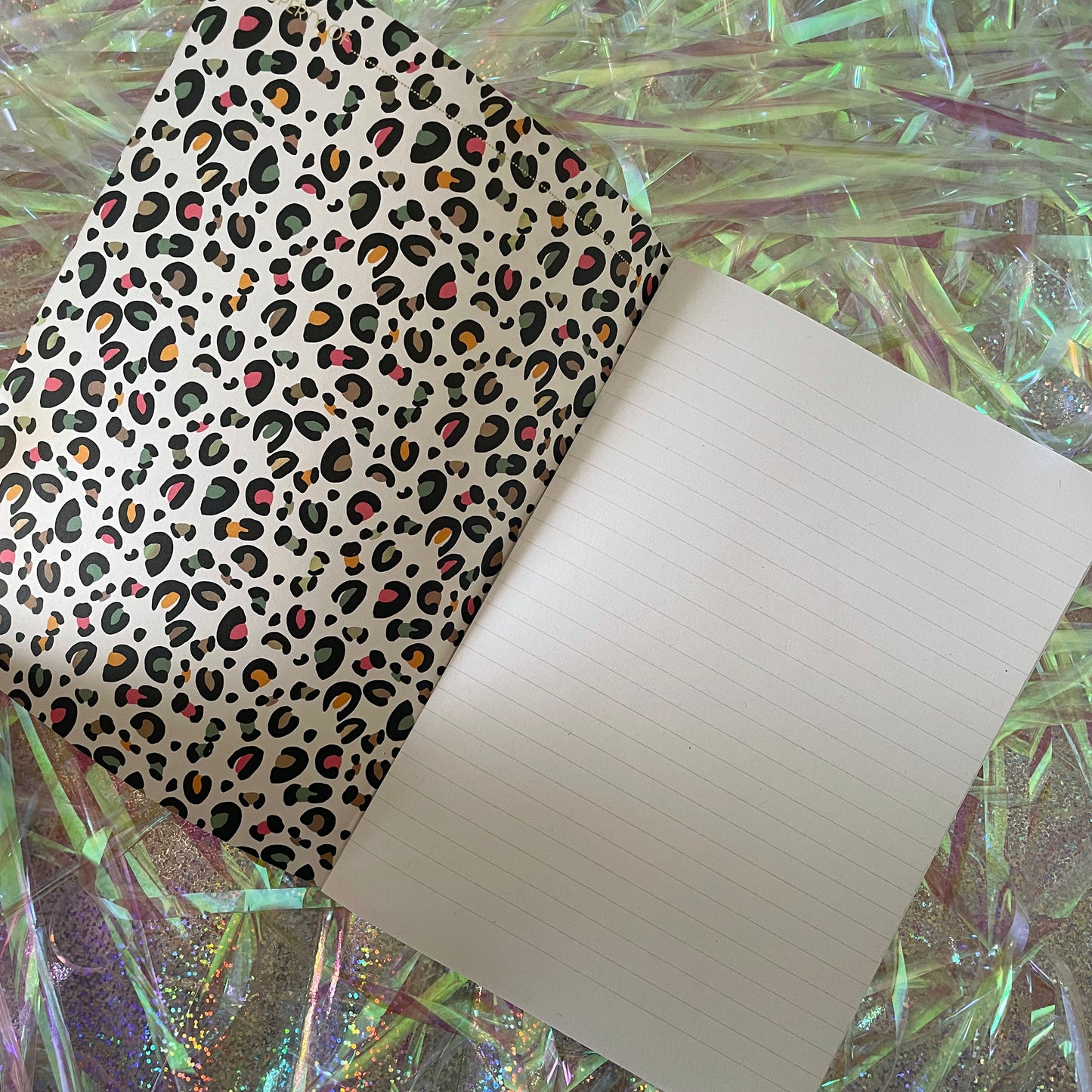 Image of a leopard print A5 size notebook in a cream colour with pops of neon open with lined pages and a leopard print inside cover.