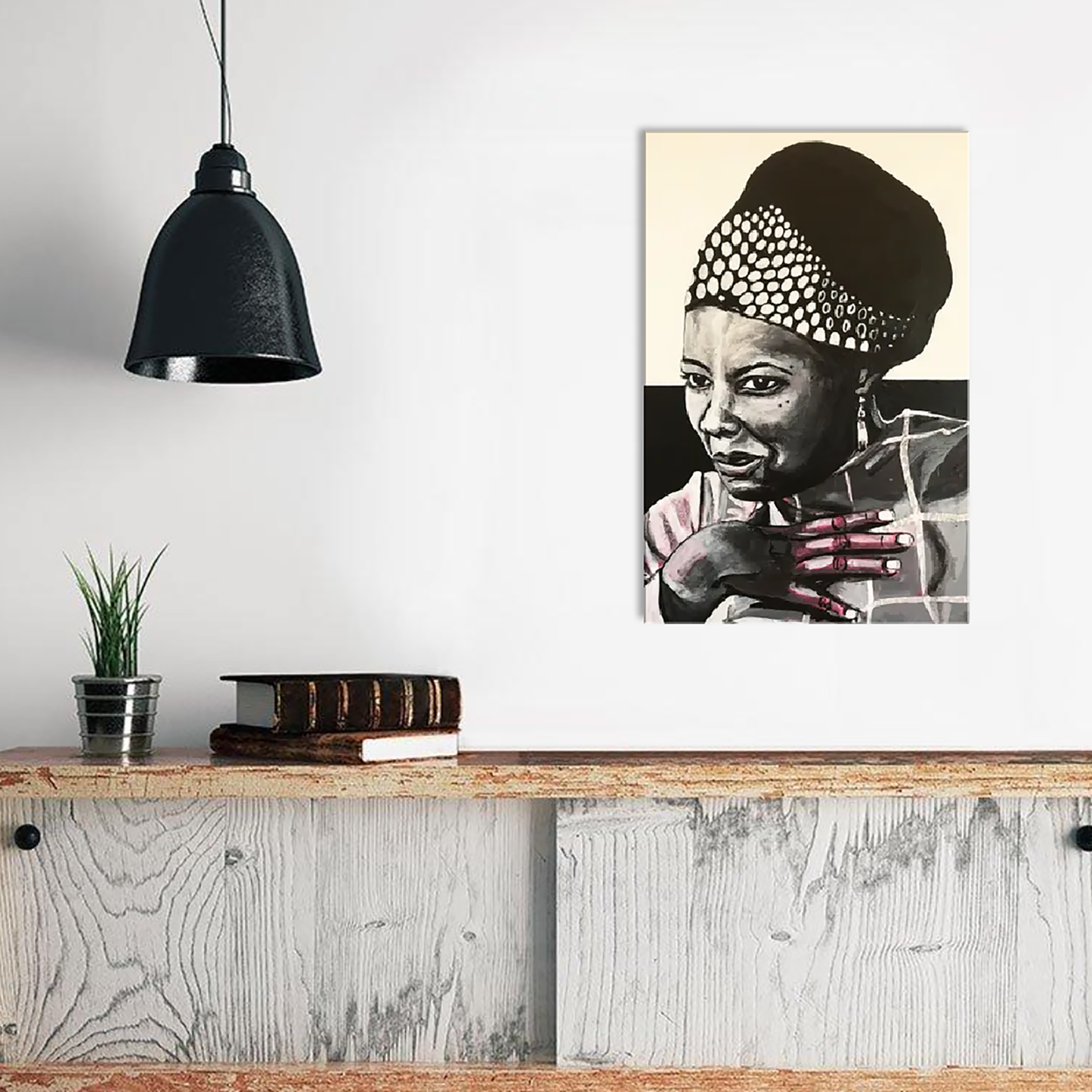 Image shows a framed black and white portrait of Maya Angelou. Artwork is painted in black and white wirth a pink undertone visible in the hand and shoulder