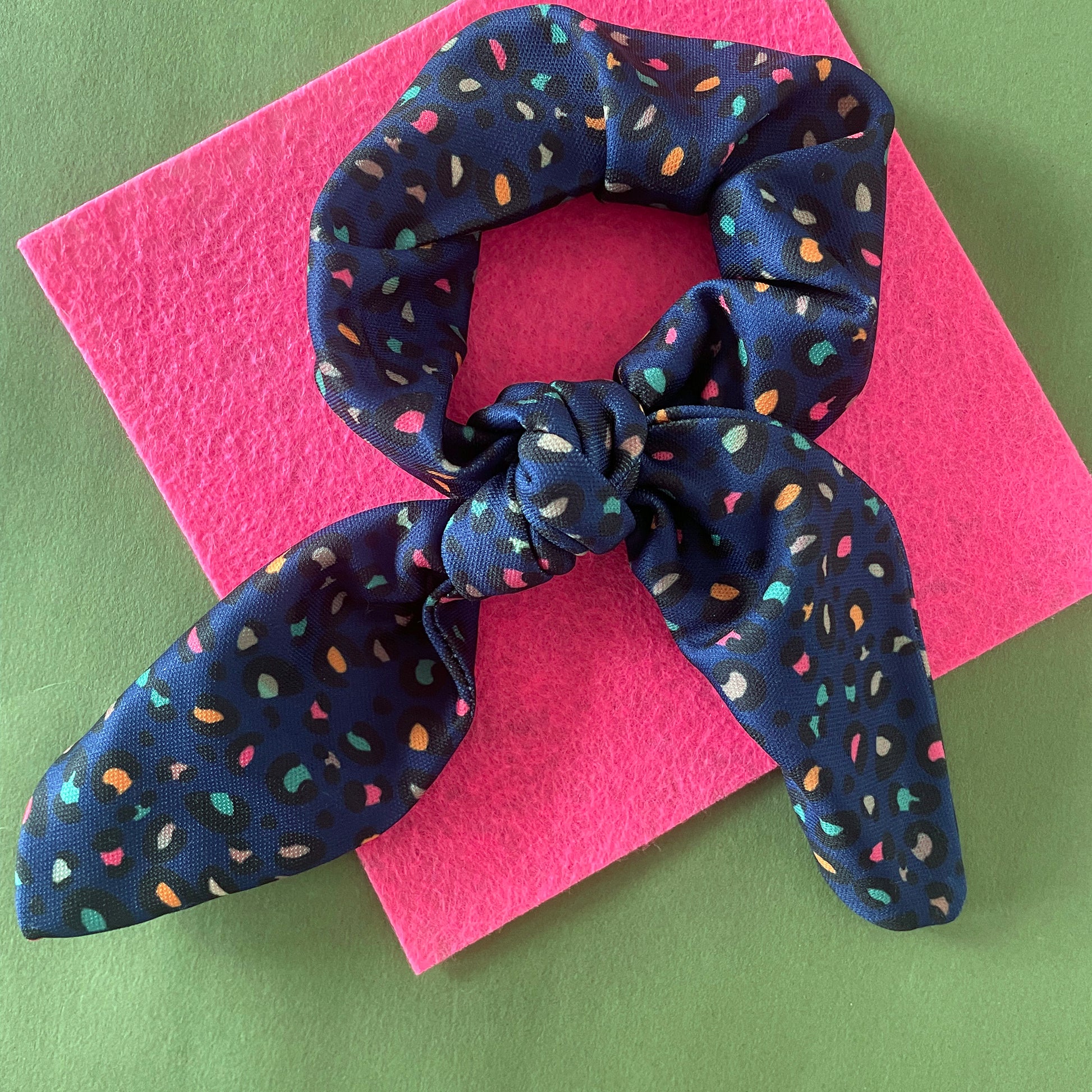 Image shows a handmade midnight blue leopard print hair scrunchie with a bow.