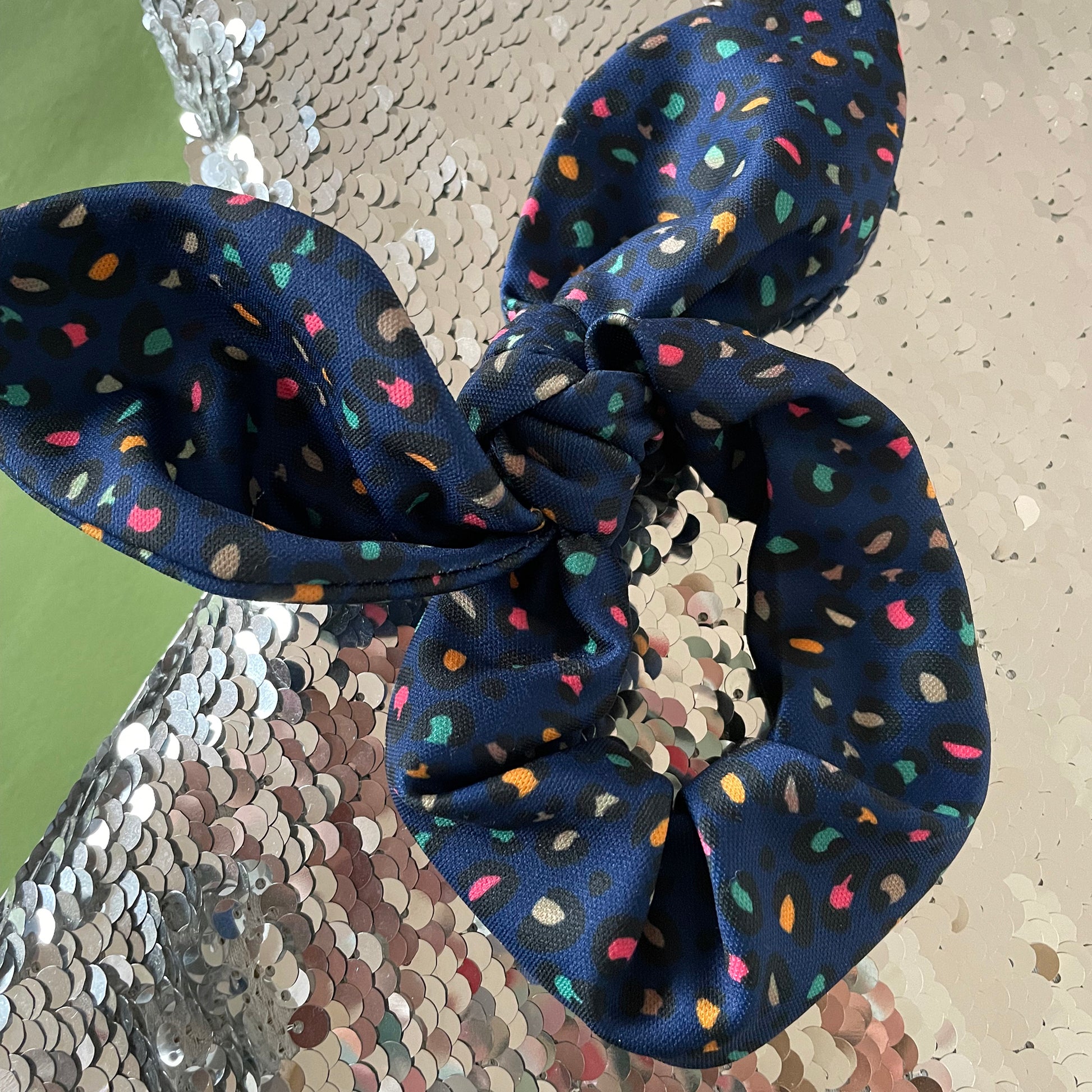Image shows a handmade midnight blue leopard print hair scrunchie with a bow.
