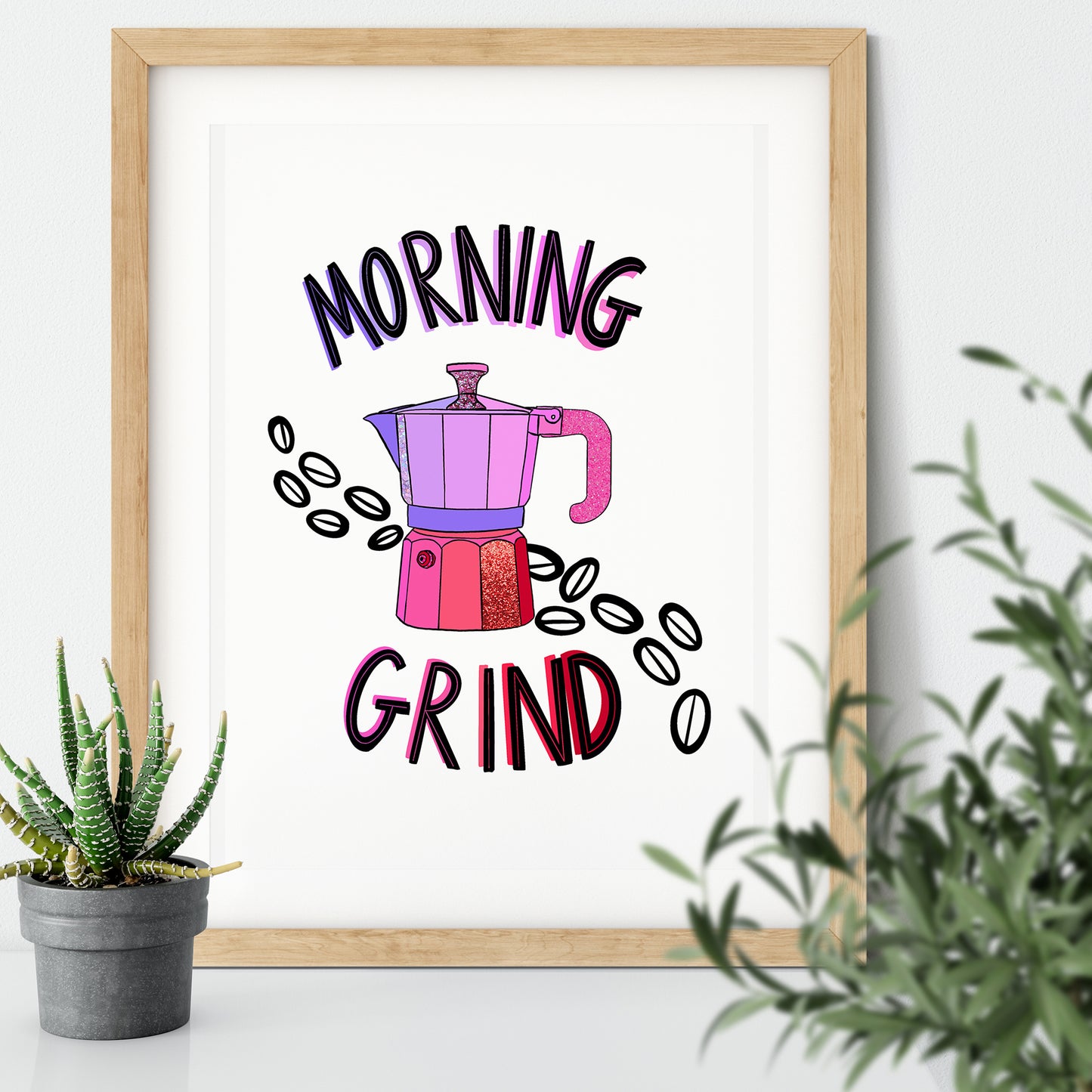 Image shows a framed illustration of a stovetop espresso maker in shades of pink and purple with ink drawn coffee beans behind it. Modern graphic lettering reads Morning Grind.