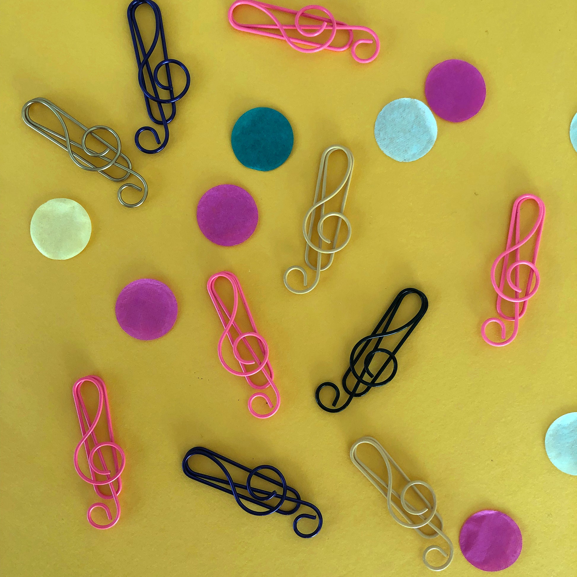 Image shows a set of pink, black and gold, treble clef shaped paperclips.