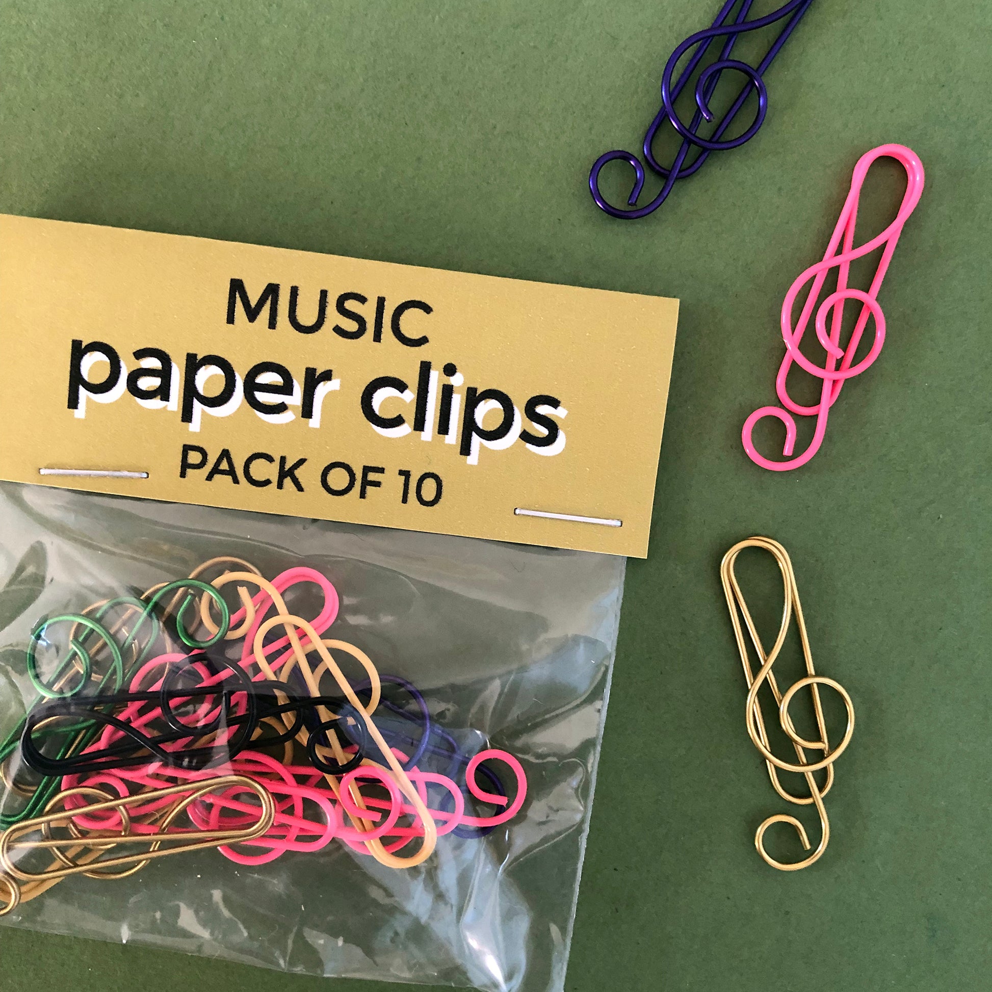 Image shows a set of pink, black and gold, treble clef shaped paperclips.