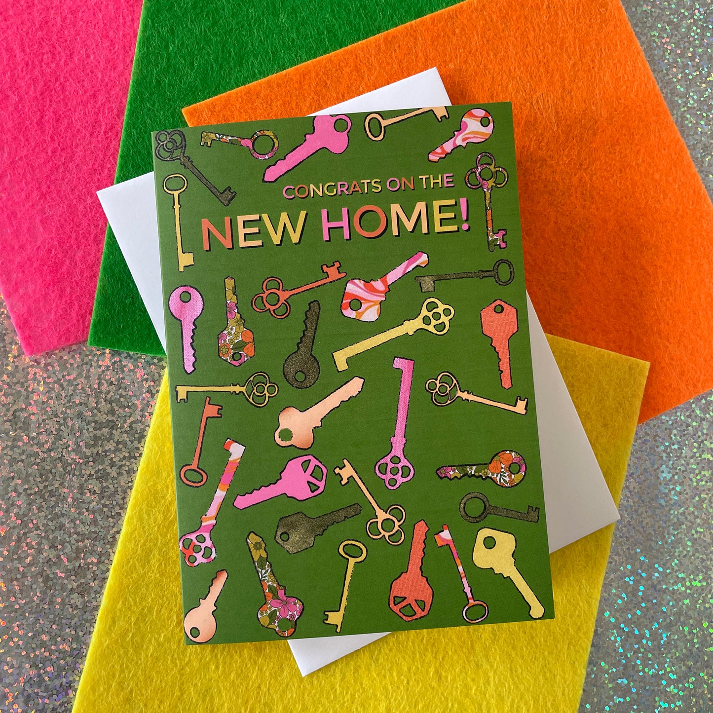 Image shows a green greetings card with a illustrations of colourful keys and the words 'Congrats on the new home'